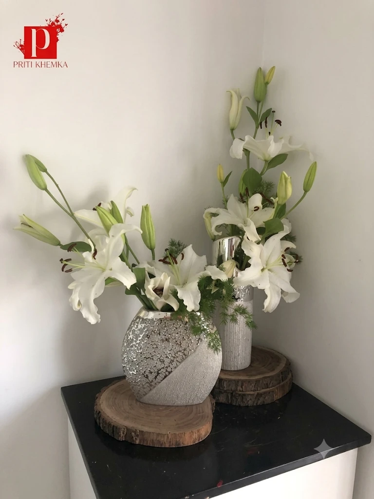 White lilies arranged in two textured vases on wood slices