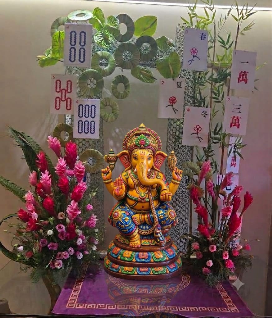 A Ganpati mandap dressed with pink ginger flowers, anthurium, bamboo and hanging mahjong cards