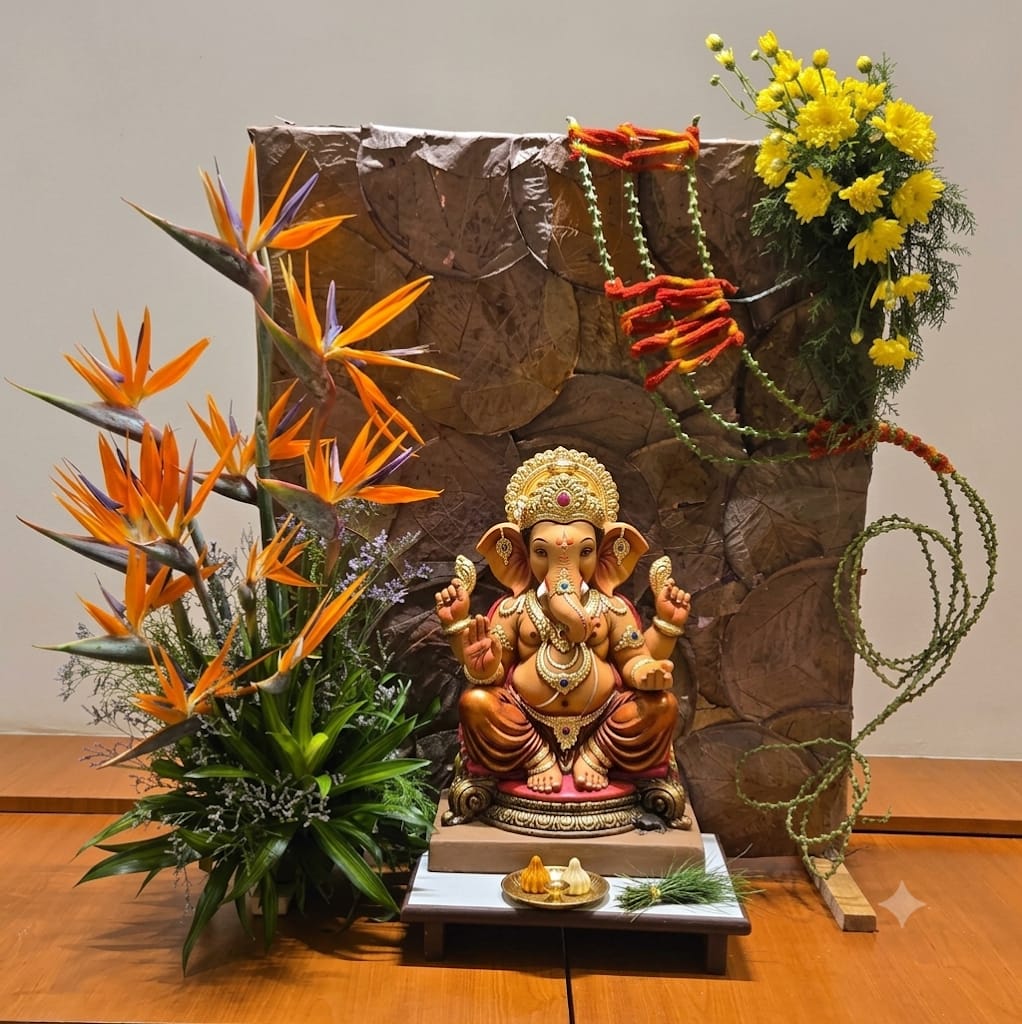 A Ganpati arrangement with bird of paradise, yellow chrysanthemum and a dried-leaf screen