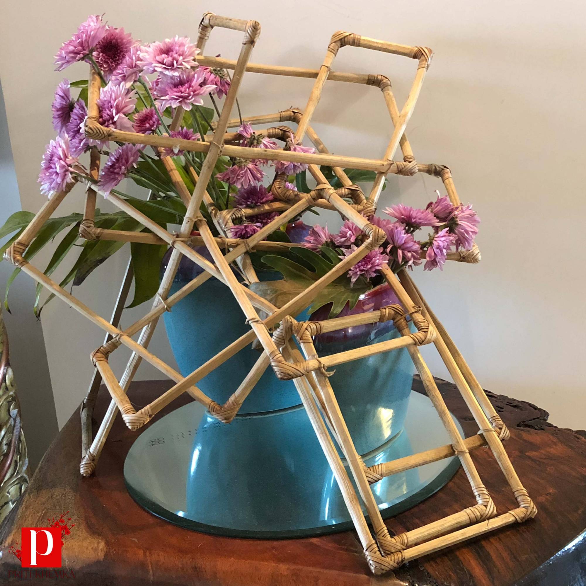 A woven bamboo lattice structure with pink chrysanthemums and a turquoise vessel